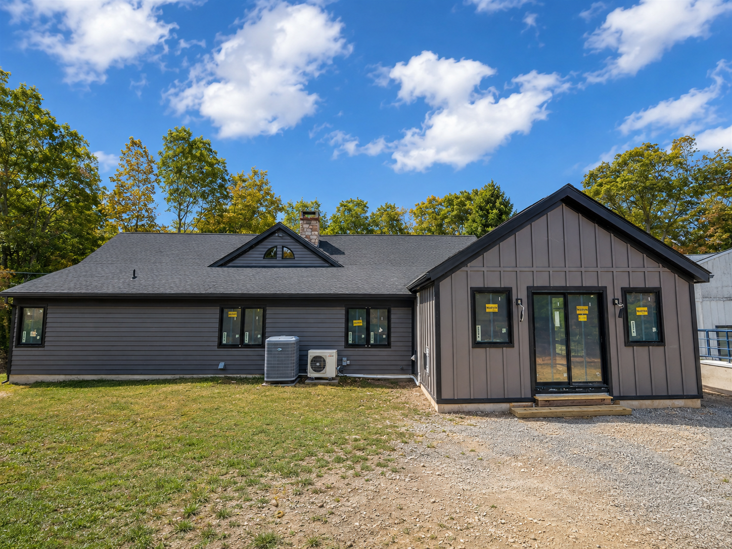 The same rear elevation after painting, with uniform charcoal siding, black window trim and a finished board-and-batten wing