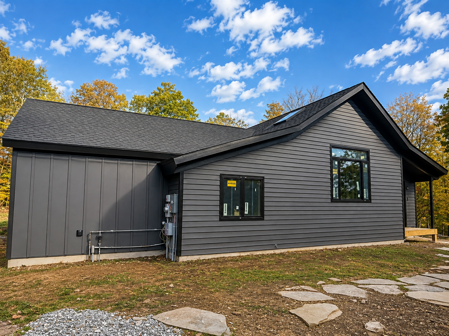 The same side of the house after painting, with charcoal lap siding and a matching board-and-batten wing